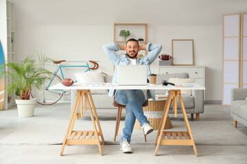 Freelance worker resting in front of his laptop at home