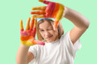 © Pixel-Shot - Smiling teenage girl with hands in paint on turquoise background