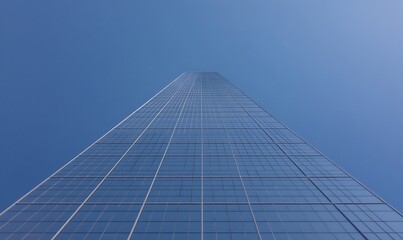 Poster - A towering glass skyscraper reaching towards the blue sky from an upward angle.