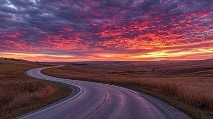 Poster - A winding road with a car driving into the distance, framed by a vibrant sunset sky.