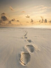 Poster - Serene sunset on an empty beach with footprints leading to the horizon and a tranquil sky for reflections Generative AI