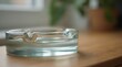 © Kristina - Close-up of an empty glass ashtray on a wooden table