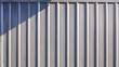 © Prapat - Gray corrugated metal exterior wall background of warehouse building or cargo container with light and shadow on surface