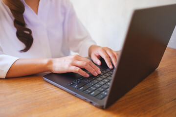 Wall Mural - closeup image of a woman working and typing on laptop computer keyboard
