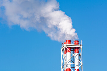 industrial chimneys release thick white smoke into the atmosphere, creating a strong contrast with t