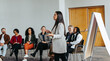 © Jacob Lund - Female instructor leading teambuilding session with diverse group in modern office setting