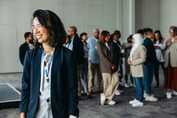 Wall Mural - diverse crowd at a business conference with a smiling professional woman in the foreground