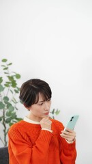 Aufkleber - リビングルームで悩みながらスマホを見るミドル女性