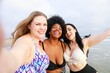 © Rawpixel.com - Three women at the beach, smiling and taking a selfie. Women enjoying the beach, diverse ethnicities. Beach, women, and smiles in a joyful selfie moment. Body positivity and inclusivity in summer.