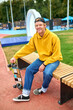 © zinkevych - Positive smiling guy in yellow hoodie sitting on the bench