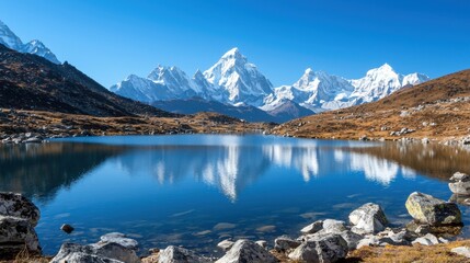 Wall Mural - Snow-covered peaks rise majestically around a tranquil lake. The crystal-clear waters mirror the mountains, creating a stunning display of nature in bright daylight