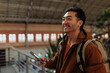 © bernardbodo - Smiling tourist using smart phone app in train station