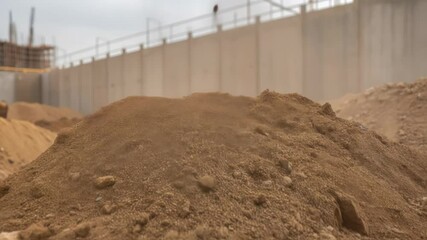 Aufkleber - Swirling dust cloud rising from large soil pile at construction site, wind creating hazy atmosphere near concrete retaining wall with blowing earth particles