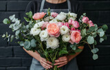Florist holding a stunning bouquet of pink and white ranunculus with eucalyptus leaves. Elegant floral arrangement, perfect for weddings, celebrations, and romantic gifts