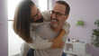 © Krakenimages.com - Middle-aged hispanic couple smiling and embracing in a cozy living room reflecting love, family, and togetherness indoors with man and woman enjoying each other's company.