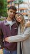 © Krakenimages.com - Couple embracing outdoors with city backdrop highlighting love and companionship of a young man and woman together on an urban street in a vibrant town setting