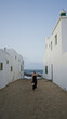 © Krakenimages.com - Woman walking between white houses towards the beach in famara, lanzarote, showcasing a serene outdoor scene with a young hispanic woman enjoying the coastal ambiance at sunset.