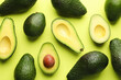 © New Africa - Whole and cut avocados on light green background, flat lay