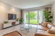 © malayeka - Modern living room with patio access.  Bright, spacious, and inviting interior.  Large windows showcasing a lush green backyard.  Relaxing atmosphere with comfortable furnishings and natural light.