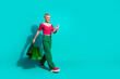 © deagreez - Stylish young woman with shopping bags checks her phone against a vibrant turquoise background