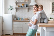 © InsideCreativeHouse - Cute little small kid child son embracing hugging his pregnant young mother mom in the kitchen. Spending morning together, family time. Children care. Happy motherhood