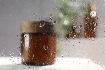 Wall Mural - body care product in jar on table, view through wet glass. space for text