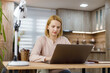 © Marko - Woman working on laptop at home in cozy setting