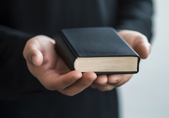 Poster - Person holding a classic black book symbolizing knowledge and wisdom with a soft blurred background : Generative AI