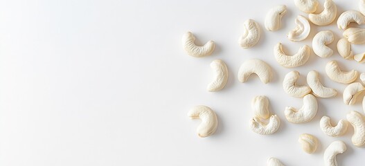 Poster - A scattered arrangement of raw cashew nuts on a clean white background illustrating healthy snacking : Generative AI