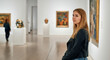 © Postmodern Studio - Young caucasian female exploring art gallery with modern paintings and sculptures