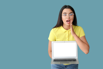 Wall Mural - shocked young female programmer with laptop on blue background