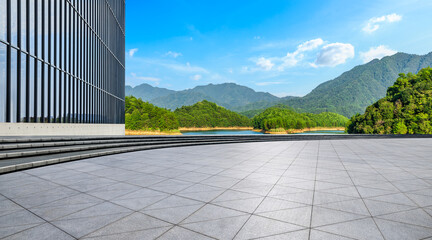 Wall Mural - empty square floor and glass wall building with green mountain under blue sky