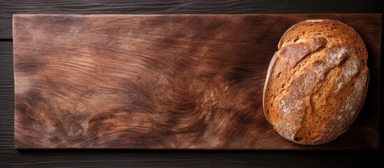 Poster - Rustic top view of a slice of golden rye bread on a dark wooden cutting board with ample copy space on the left side of the image