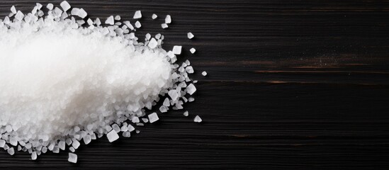 Poster - Close-up of white sea salt crystals scattered on a dark wooden surface with ample copy space for product placement or text enhancement