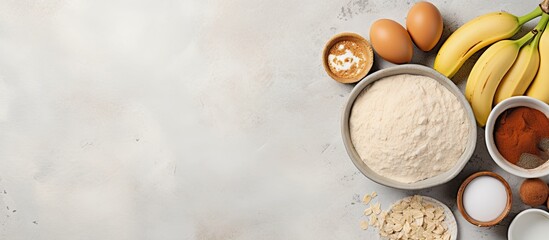 Poster - Top view of a light gray surface featuring bowls of flour, sugar, eggs, bananas, and cinnamon for banana bread with ample copy space on the right
