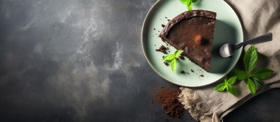 Poster - Chocolate dessert on a green plate with a slice removed, surrounded by fresh mint leaves and coffee grounds, natural light on a dark textured background.