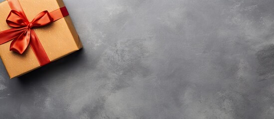 Poster - Top view of a brown gift box with a red ribbon on a textured gray concrete surface creating ample blank space for text or images