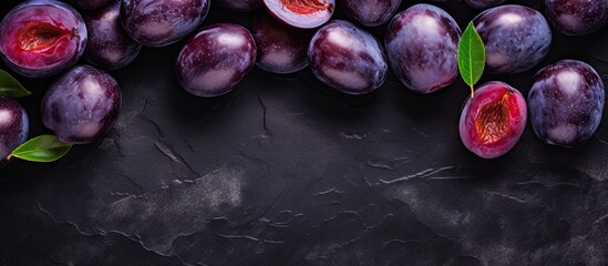 Poster - Fresh ripe plums with deep purple skin and vibrant red flesh arranged on a dark textured background, accented by green leaves for contrast.