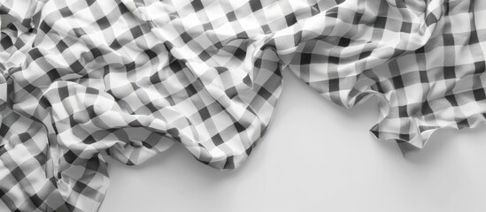 Fototapete - Crumpled black and white checkered fabric on a light grey background with ample copy space for design or textile related concepts.