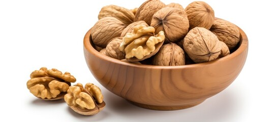 Poster - Top view of a wooden bowl filled with whole walnuts resting on a white background with a few walnut halves nearby perfect for text placement