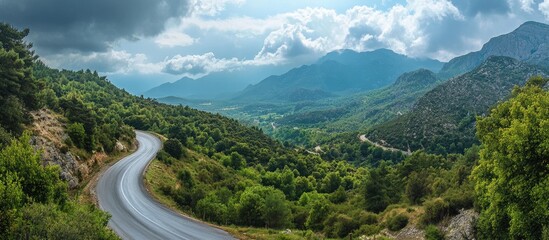 Aufkleber - Serene aerial view of a winding countryside road surrounded by lush green forests and majestic mountains under a partly cloudy sky.