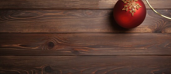 Poster - Christmas ornament in red color on dark wooden surface with ample copy space on the right side creating a festive and warm atmosphere.