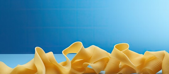Poster - Colorful assorted pasta shapes in spiral and bow forms arranged against a vibrant blue background with ample copy space for text inclusion.