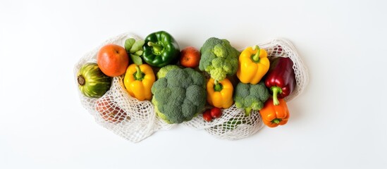Poster - Colorful arrangement of broccoli, bell peppers in green, yellow, orange, red, with tomatoes on white background in a netted bag.