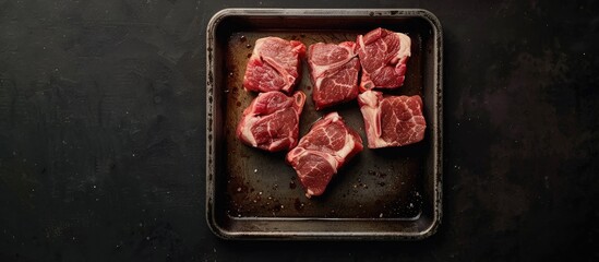 Poster - Raw lamb neck pieces arranged on a steel tray center stage on a black background with ample copy space for culinary or meat marketing use.