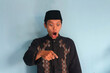 © Lailar Studio - Young Asian Muslim man looking down while pointing with surprised expression