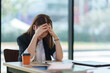 © crizzystudio - Stressed businesswoman holding head in hands at office desk
