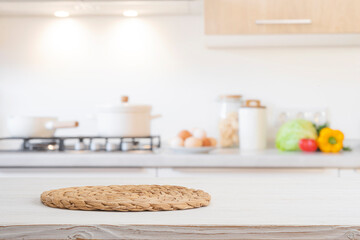 Wall Mural - woven round stand for hot dish on bleached wooden table over blurred kitchen room cooking counter ba