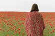 © Purple_Lamp - Woman in Blanket Overlooking Vibrant Poppy Field on Tranquil Day