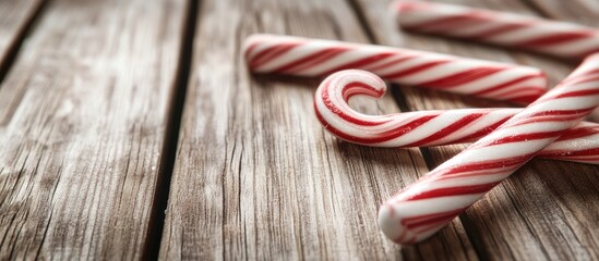 Poster - Christmas candy canes with red and white stripes scattered on a rustic wooden background creating a festive atmosphere with ample copyspace.